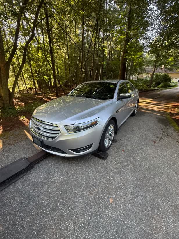 Silver sedan being loaded on a wooded driveway